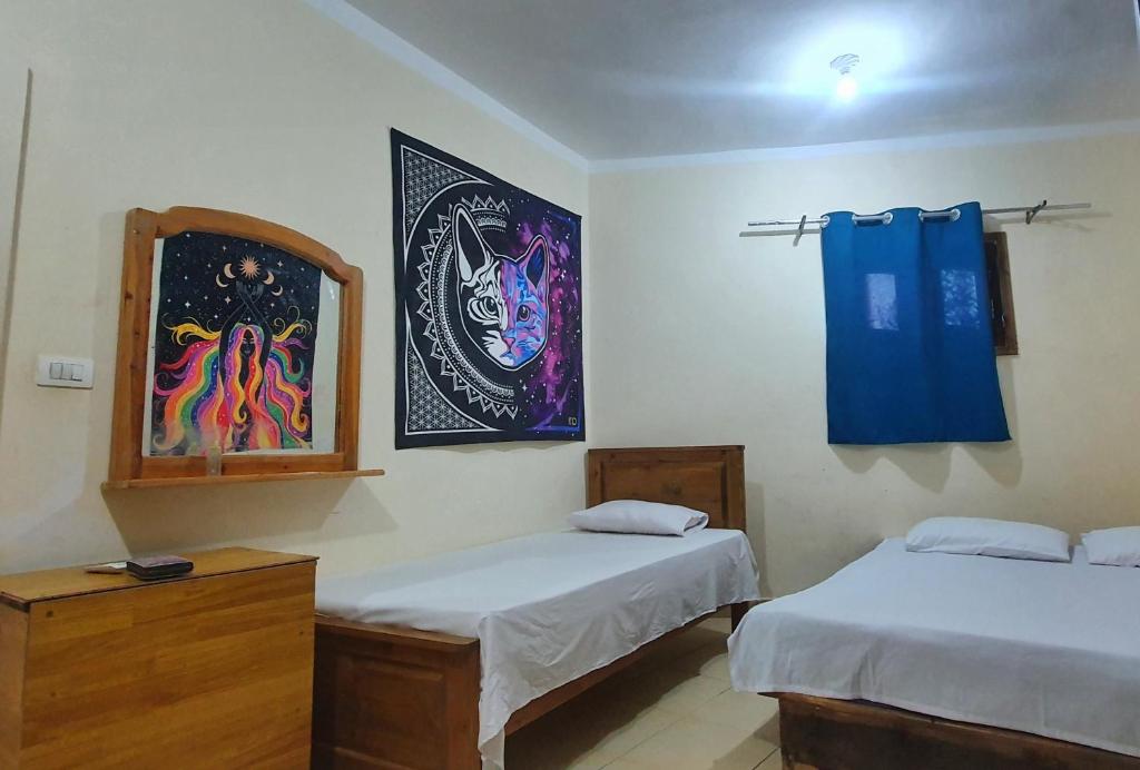 Cette chambre comprend deux lits et un tableau mural. dans l'établissement Dahab house apartment, à Dahab
