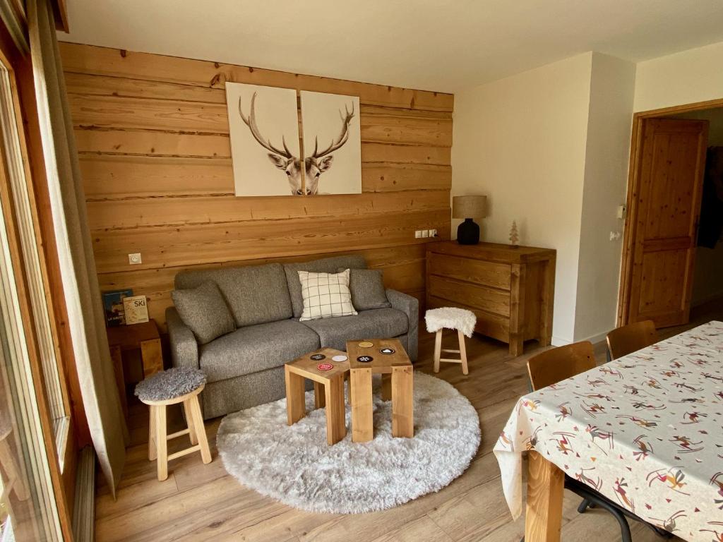 een woonkamer met een bank en een tafel bij Appartement rénové T2, vue montagne in Samoëns