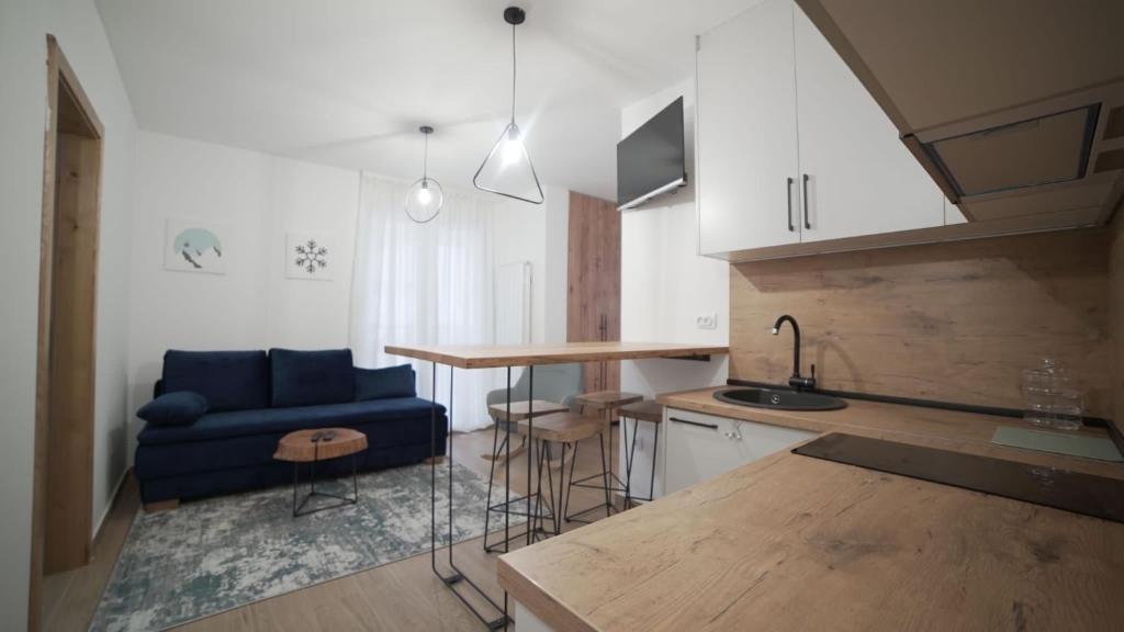 a kitchen with a blue couch and a table at Madulo apartman in Jahorina