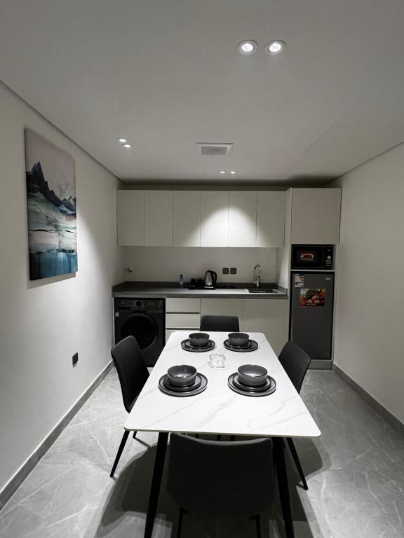 リヤドにあるالحزم للشقق الفندقية - الرياض - العلياのキッチン(白いテーブル、椅子付)