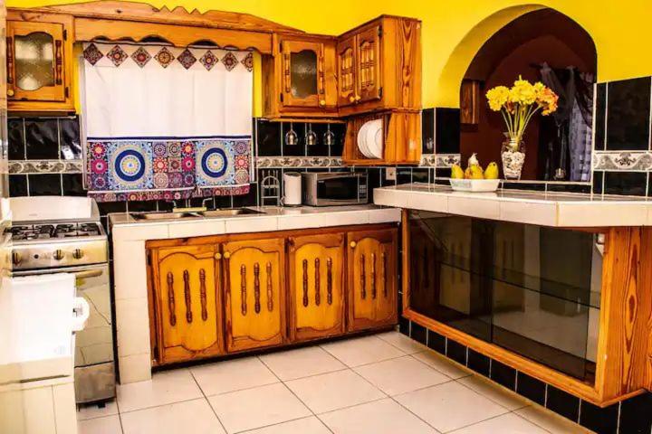 una cocina con armarios de madera y una pared amarilla en Cocklestop Inn, Jamaica, en Pond Side