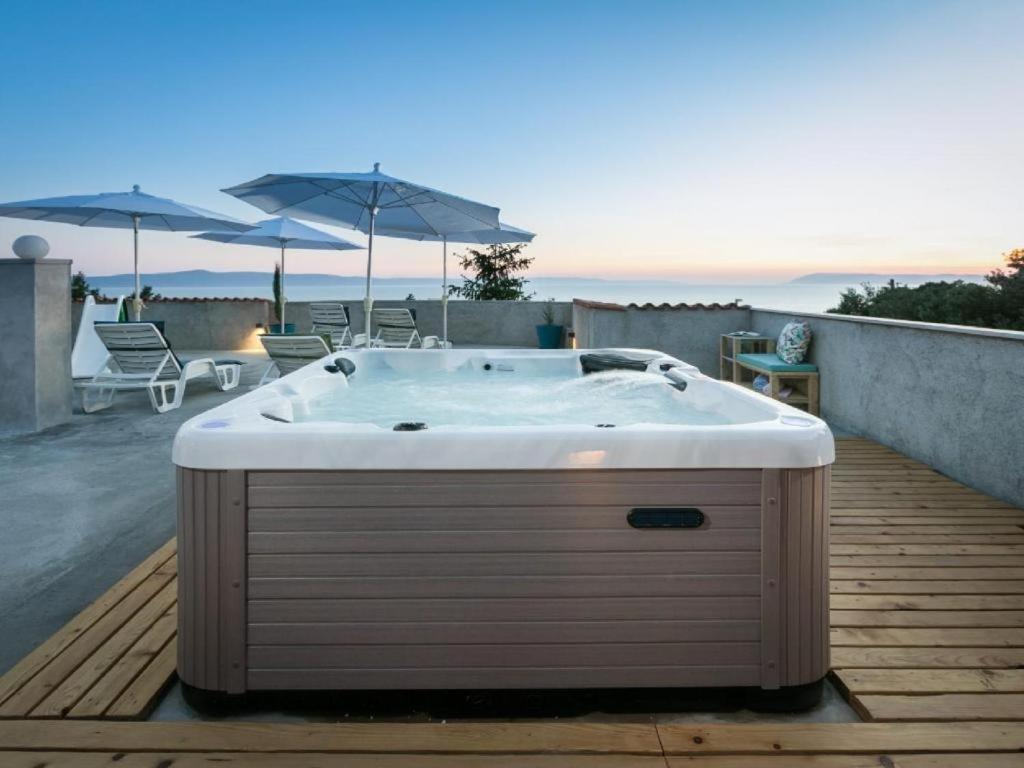 a bath tub sitting on a deck with umbrellas at Apartment Ela with private jacuzzi in Podgora
