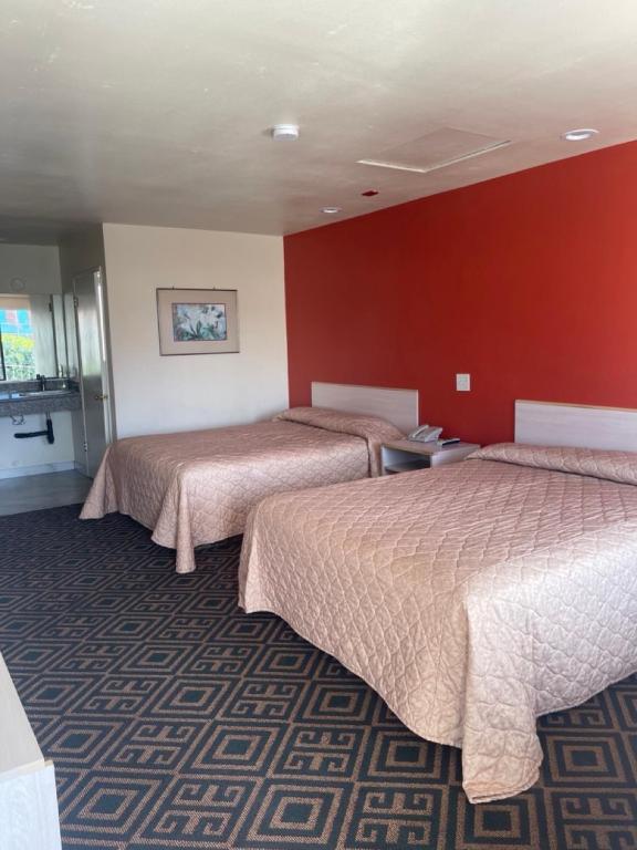 - 2 lits dans une chambre d'hôtel aux murs rouges dans l'établissement Star Lodge Motel-Oceanside, à Vista
