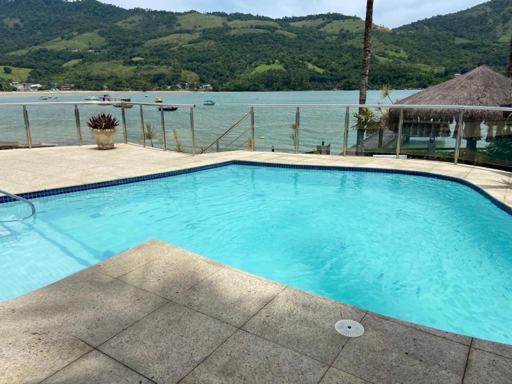 a large blue swimming pool next to the water at Angra Pier600 Casa beira mar in Angra dos Reis