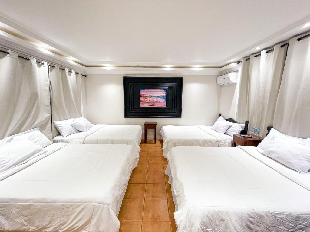 Hotel Villa Antigua في سان سلفادور: ثلاثة أسرة في غرفة ذات أغطية بيضاء
