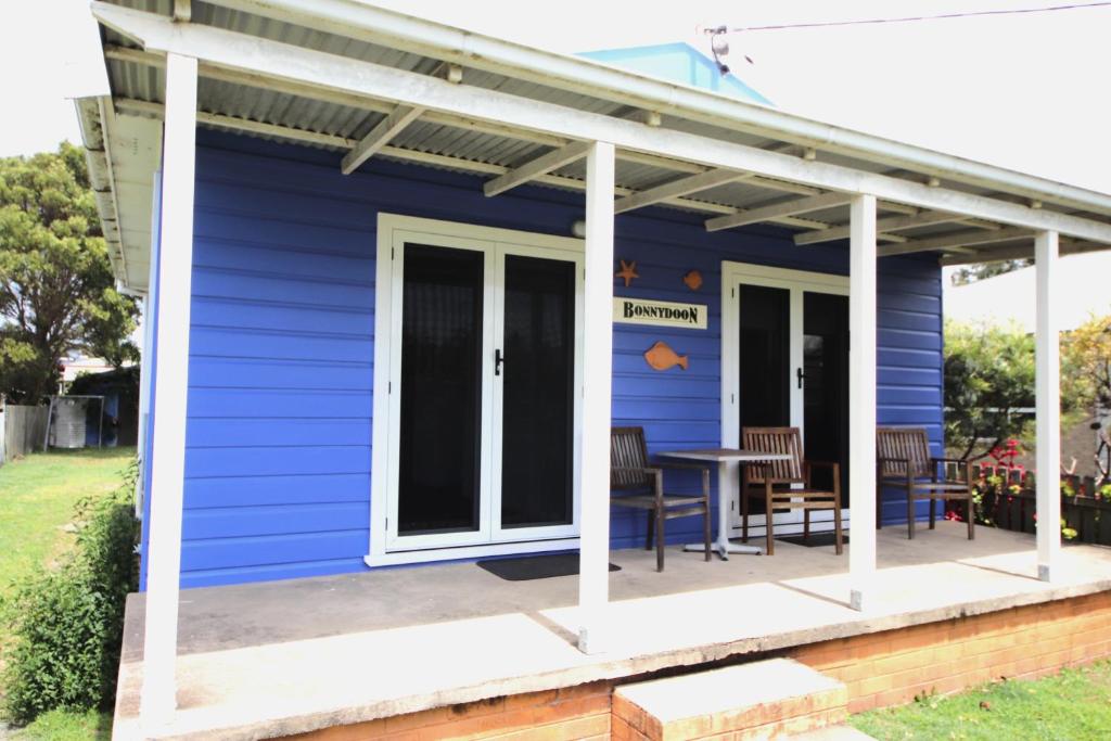 a blue house with a porch and a table at Bonnydoon at Hat Head (Pet Friendly) in Hat Head