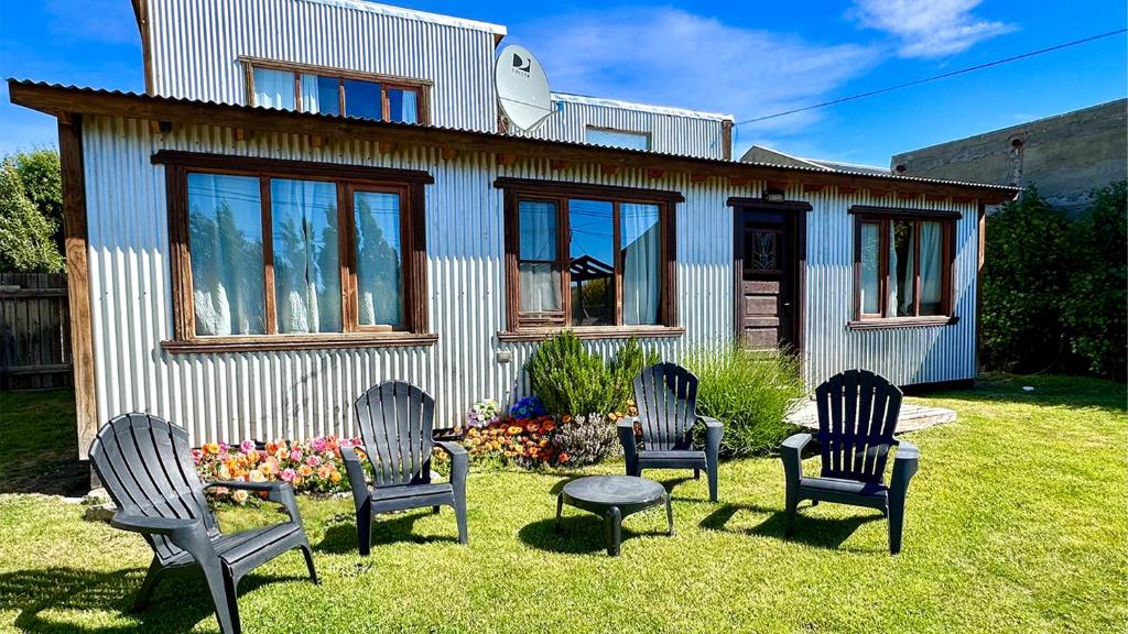 a house with four chairs and a table in the yard at Alma Andina in El Calafate