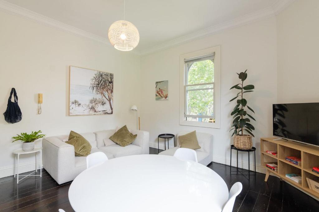 a living room with white furniture and a flat screen tv at Surry Hills Chic right on Crown St in Sydney