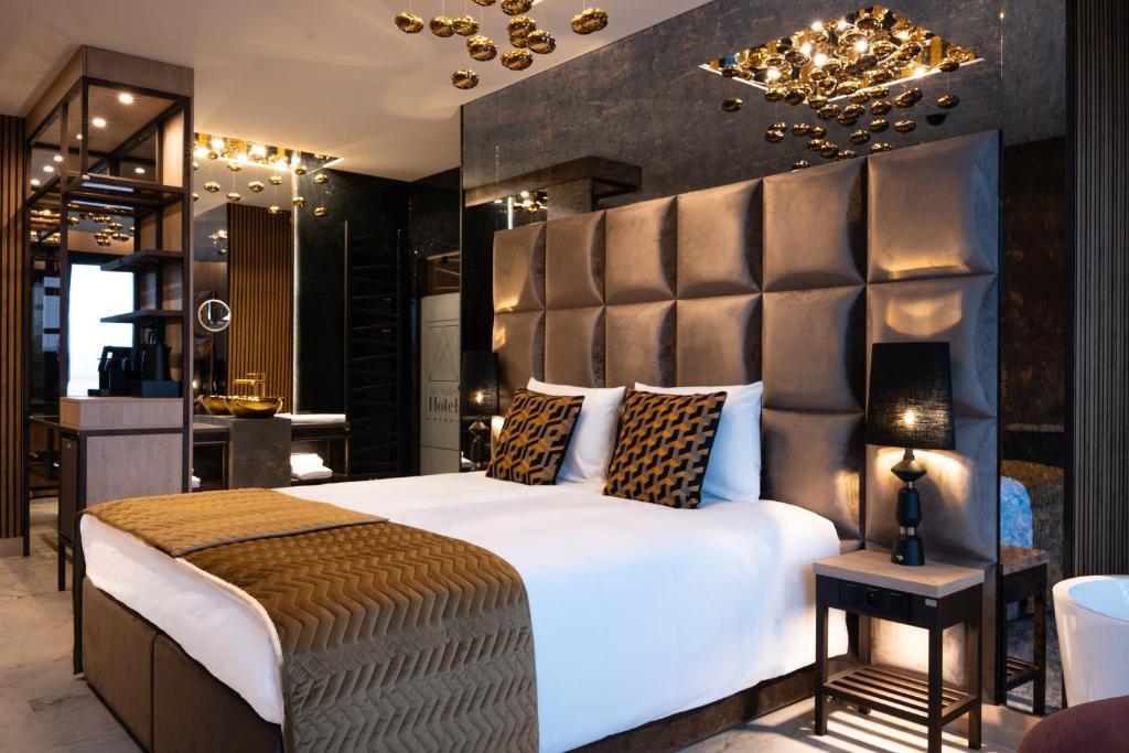 a bedroom with a large white bed and a chandelier at Art Suites Luxury Hotel in Kraków