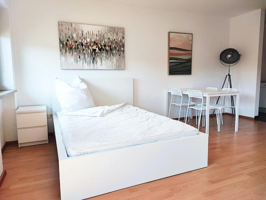 een wit bed in een kamer met een tafel en stoelen bij Apartment bei Wasserburg am Inn in Soyen