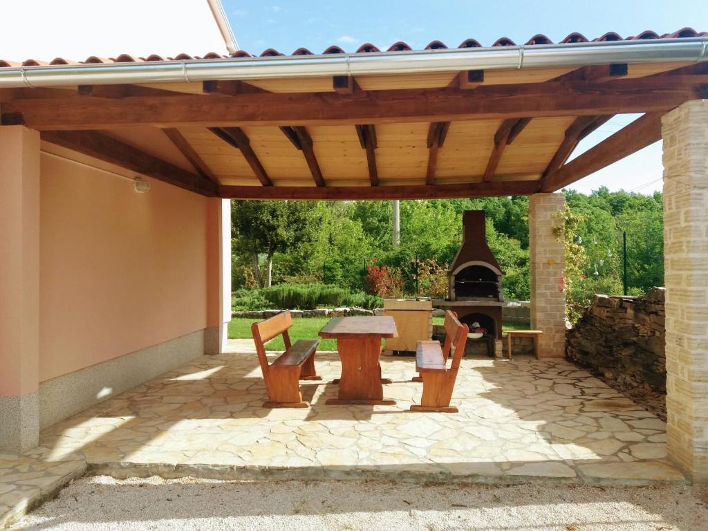 a patio with a wooden pergola with a table and a fireplace at Villa Malini in Grožnjan