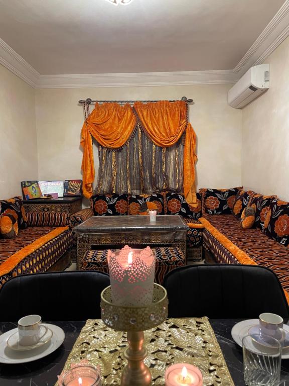 een woonkamer met banken en een tafel met een kaars bij Kech Days appartement près de l'aéroport in Marrakesh