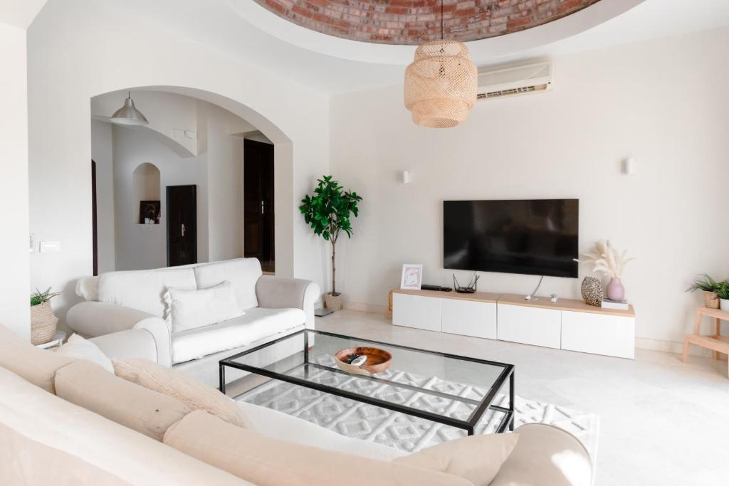 Modern Villa in El Gouna (Private Pool & Garden.) في الغردقة: غرفة معيشة بأثاث أبيض وتلفزيون بشاشة مسطحة