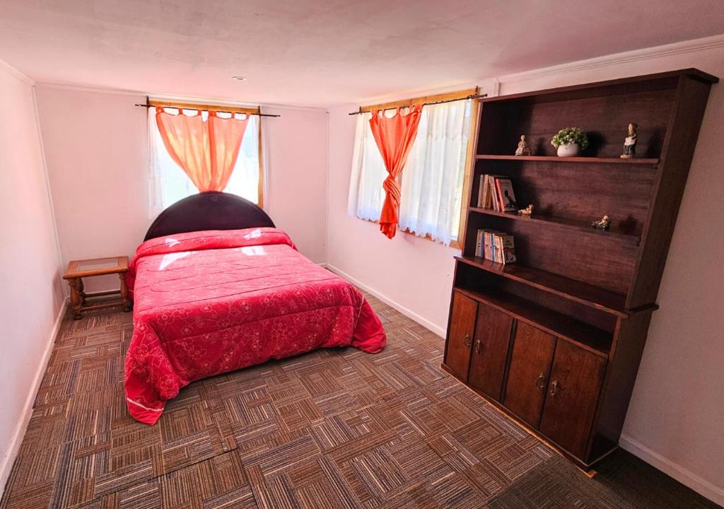 a bedroom with a bed with a red blanket at El Sauce in Curacaví