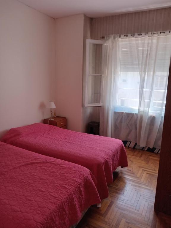 1 dormitorio con cama roja y ventana en depto pleno centro a 3 cuadras del mar en Mar del Plata