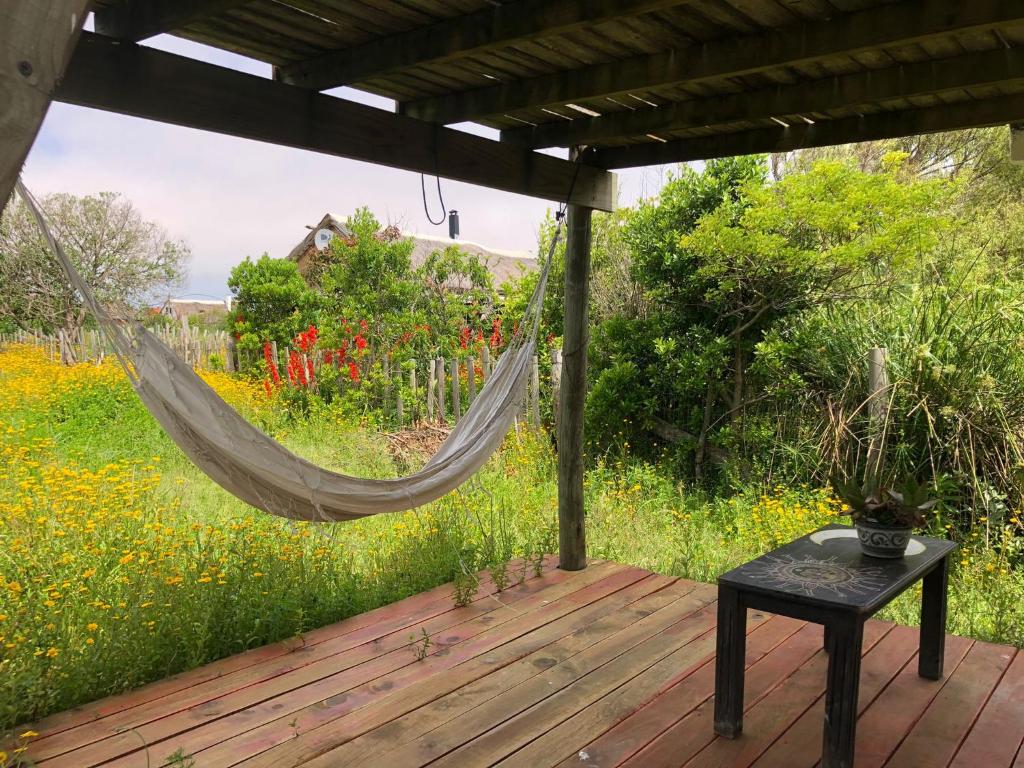 a hammock on a deck with a field of flowers at Colibrí in Barra de Valizas