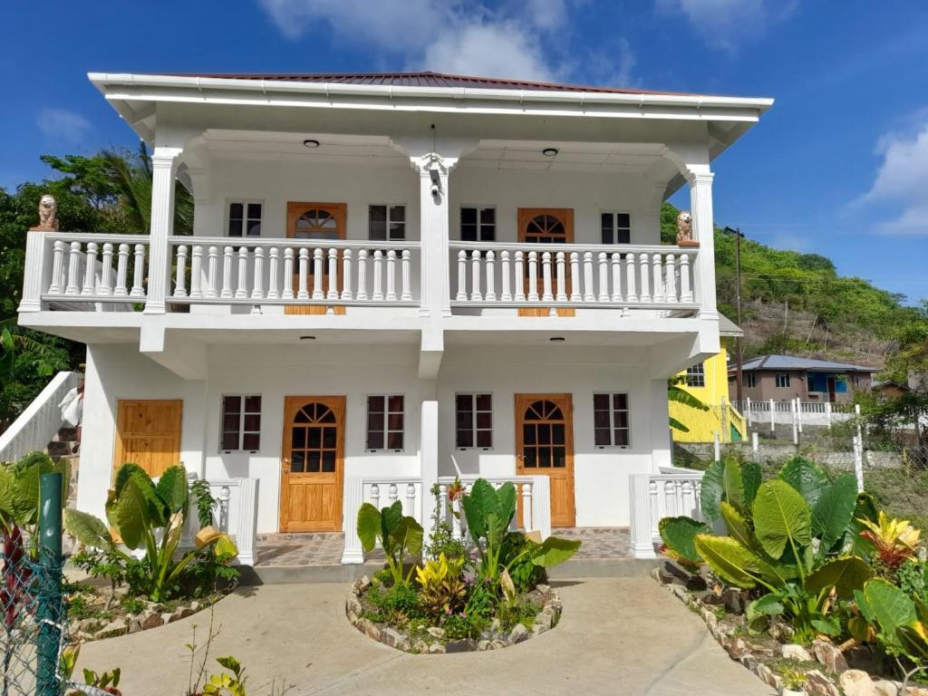 uma casa branca com uma varanda em Cool Breeze Suites em Union Island