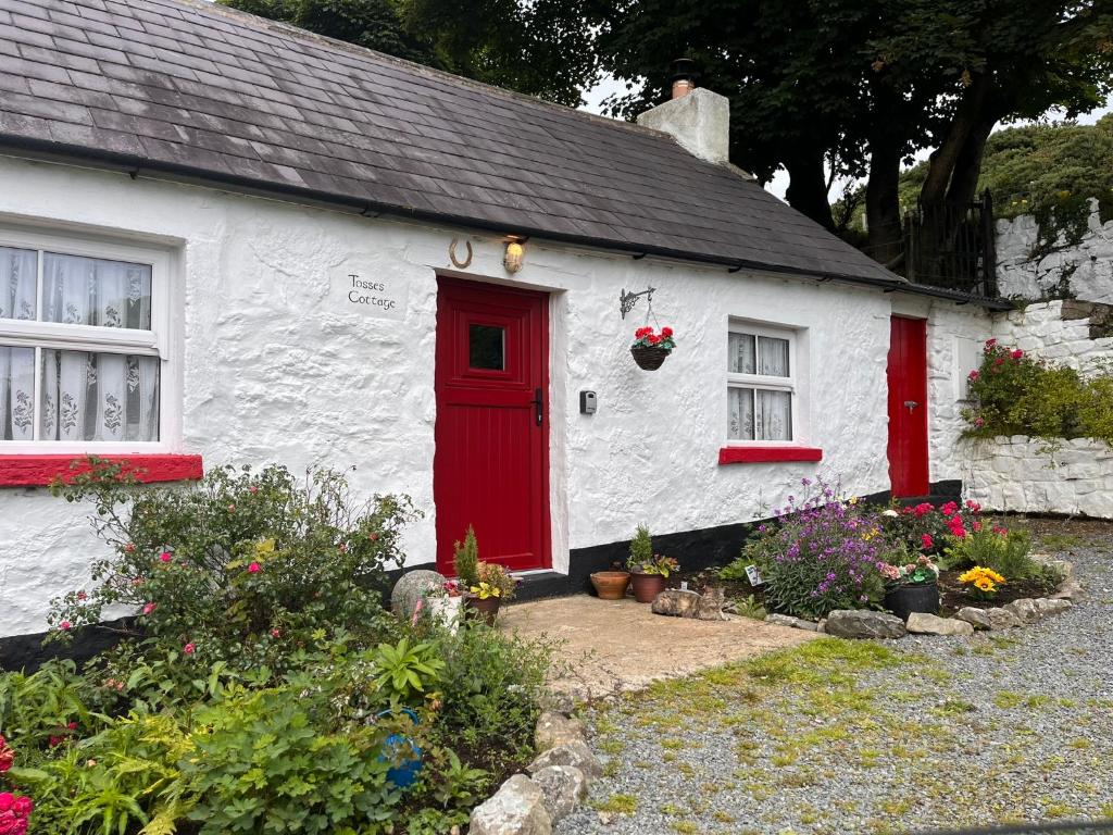 a red and white house with a red door at Tosses Cottage - Secluded cottage with hot tub in Newry