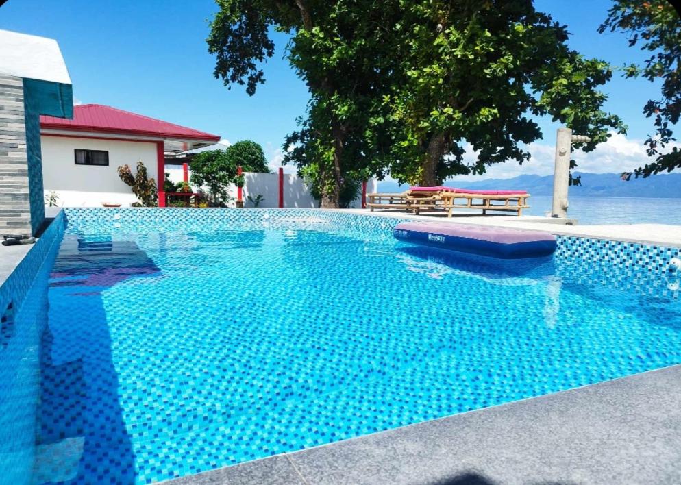 a blue swimming pool with a view of the water at Portofino Homestay in Malitbog