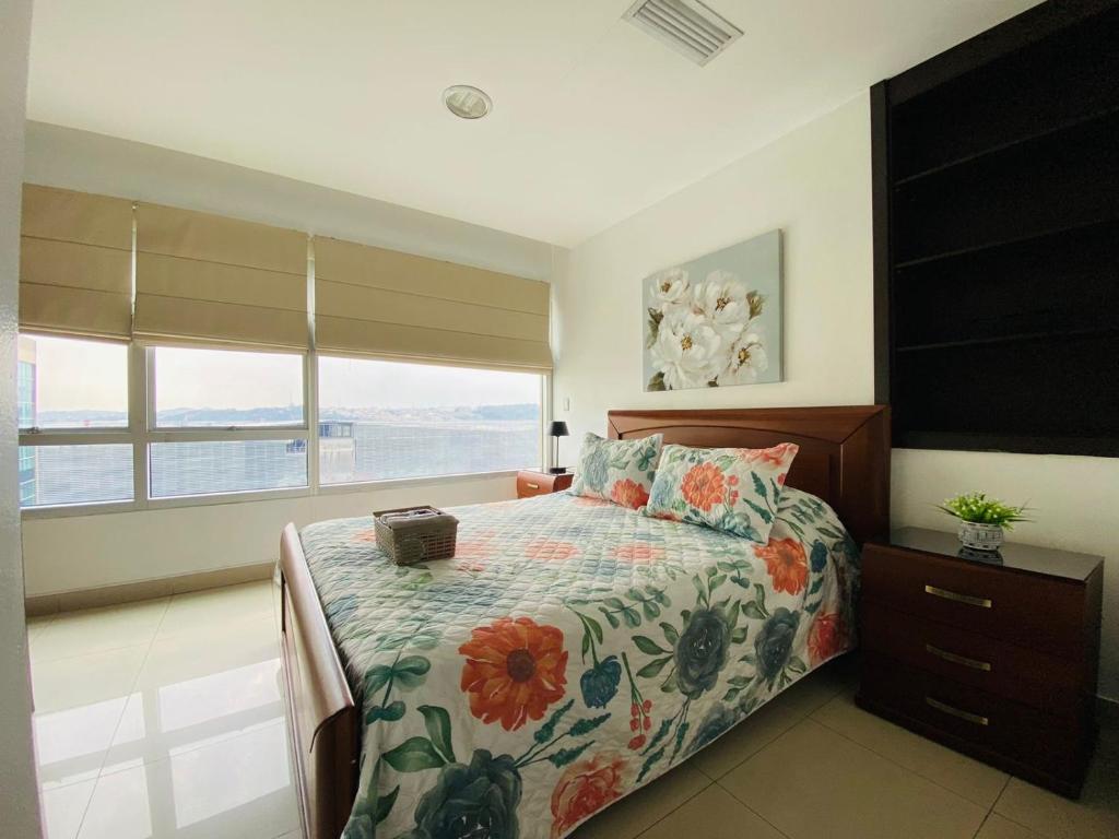 a bedroom with a bed with a floral bedspread and a window at Luxury Suite Wifi & Pool in Guayaquil