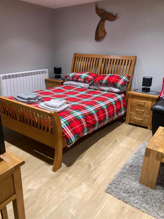 a bedroom with a bed with a red blanket and wooden furniture at Roblins Nest in Ammanford