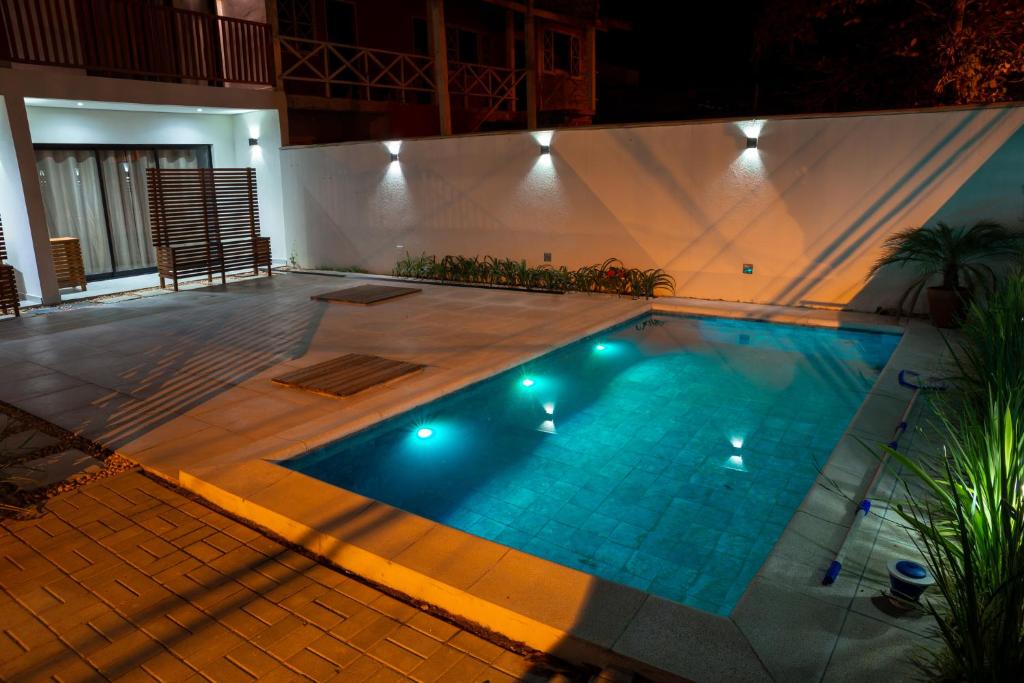 een zwembad 's nachts met verlichting bij Carolekerry Apartments in São Sebastião