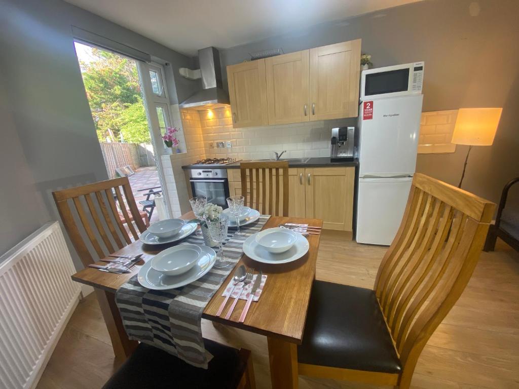 a kitchen with a wooden table with chairs and a dining room at Lovely one bedroom garden flat in Hendon in The Hyde