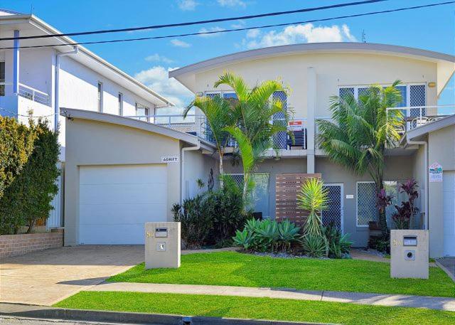 a white house with a garage and palm trees at Adrift, 5B Scott Street in Crescent Head