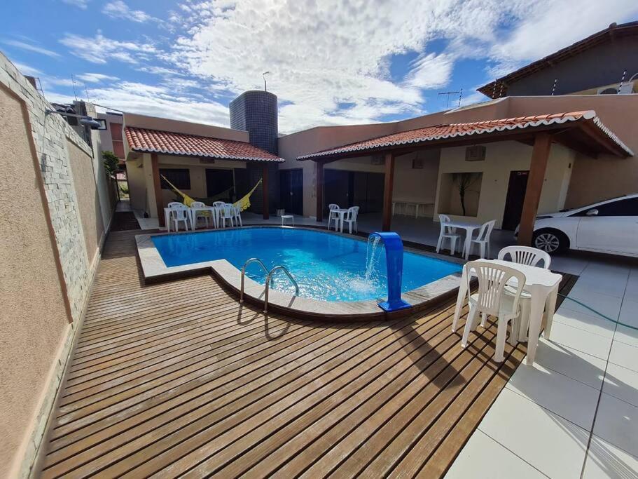 a deck with a pool and chairs and a house at Casa agradável: piscina, churrasqueira e redário. in Natal