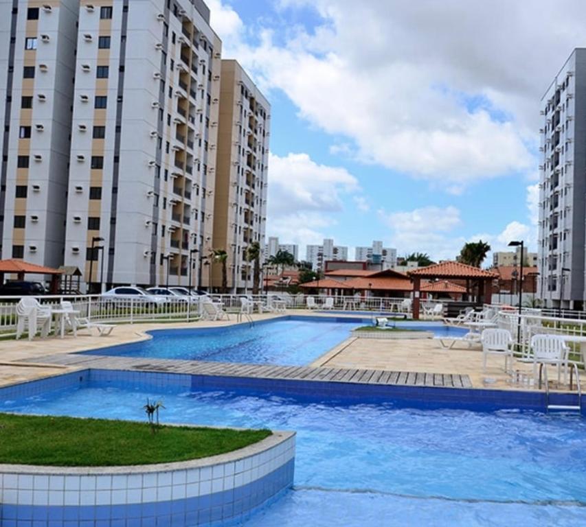 ein großer Pool mit weißen Stühlen und Gebäuden in der Unterkunft Apartamento grande próximo da praia do calhau in São Luís