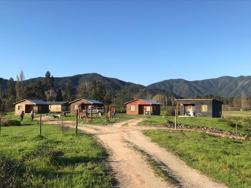 a dirt road in a field with houses and mountains at Cabañas Vista Horizonte in El Durazno