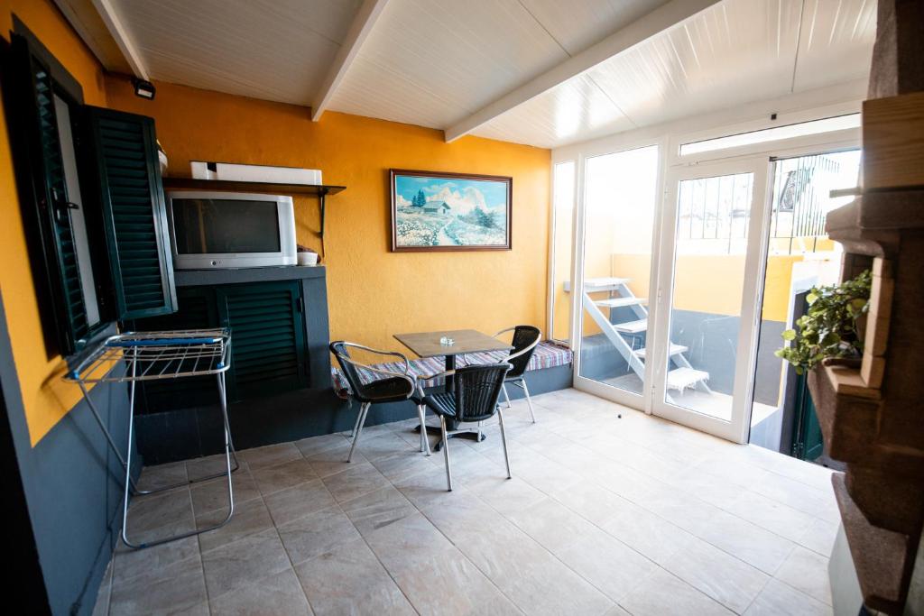 um quarto com uma mesa e cadeiras e uma televisão em Casa das Vistas em Porto Moniz