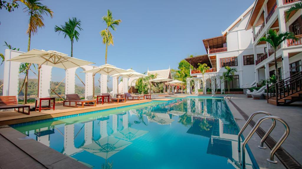 una piscina con sillas y sombrillas junto a un edificio en Relaxful Hotel泊岸酒店 en Luang Prabang