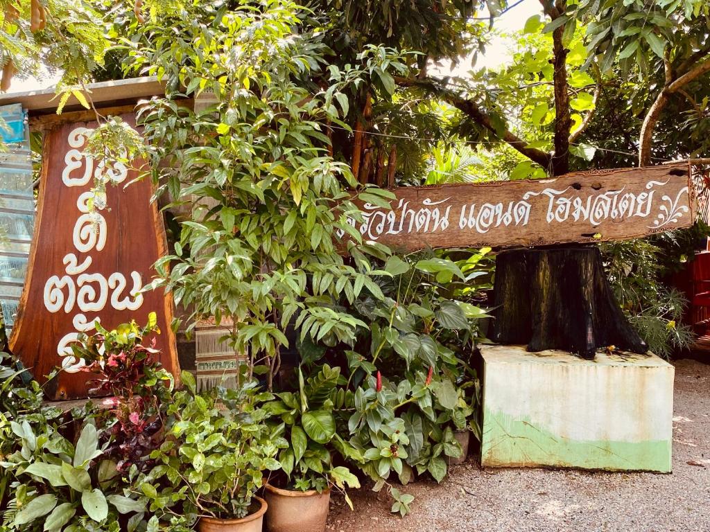 a sign in a garden with plants in pots at ครัวป่าตันแอนด์โฮมสเตย์ 