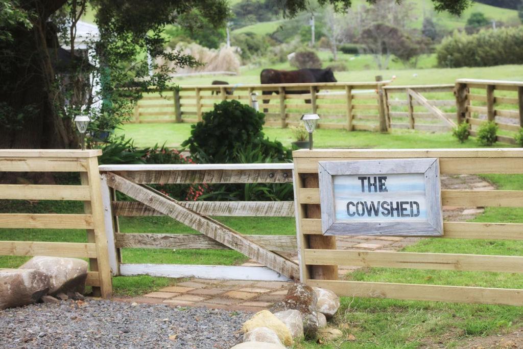 een houten hek met een bord dat de aangesloten bij The Cowshed in Whitianga