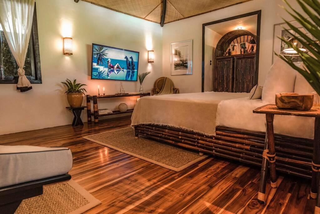 a bedroom with a large bed and a tv at Coco Bungo - Beachside Bungalow #3 in Santa Teresa Beach