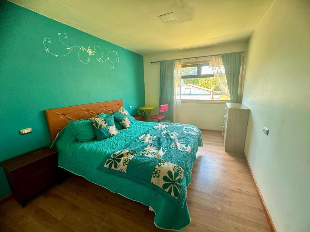 a bedroom with a bed with a green wall at Cabañas Antü 1 in Coihaique