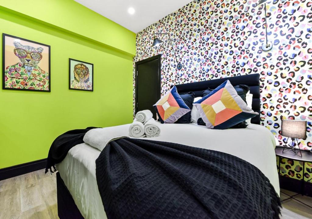 a bedroom with green walls and a bed with towels at Bright & Colourful House - Best for a Large Groups in London