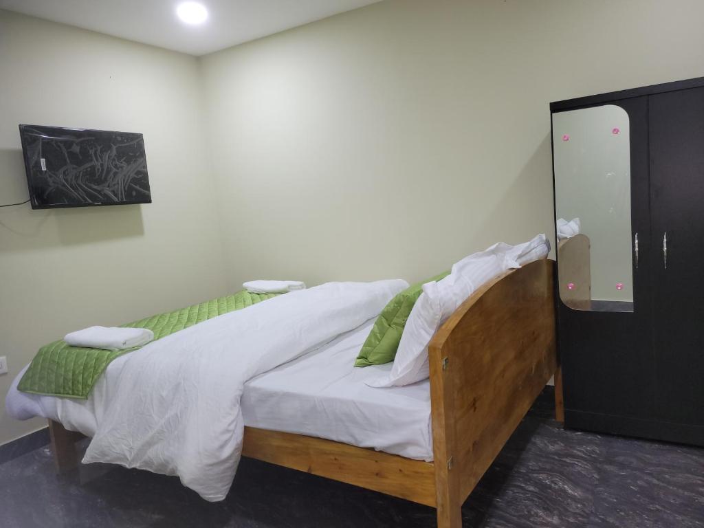 Schlafzimmer mit einem Bett mit weißer Bettwäsche und grünen Kissen in der Unterkunft Vati guesthouse in Shillong