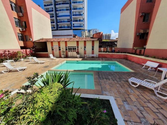 uma piscina com espreguiçadeiras e um edifício em 2 quadras do mar em Vila Velha