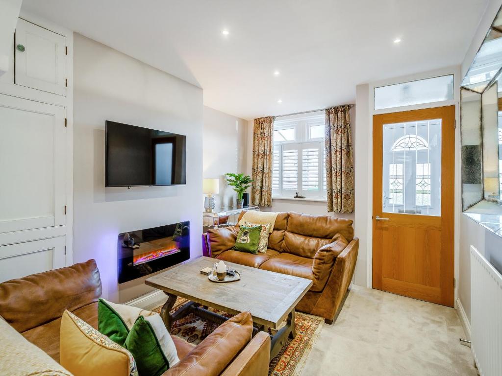 a living room with leather furniture and a fireplace at Wharfedale Cottage in Harrogate