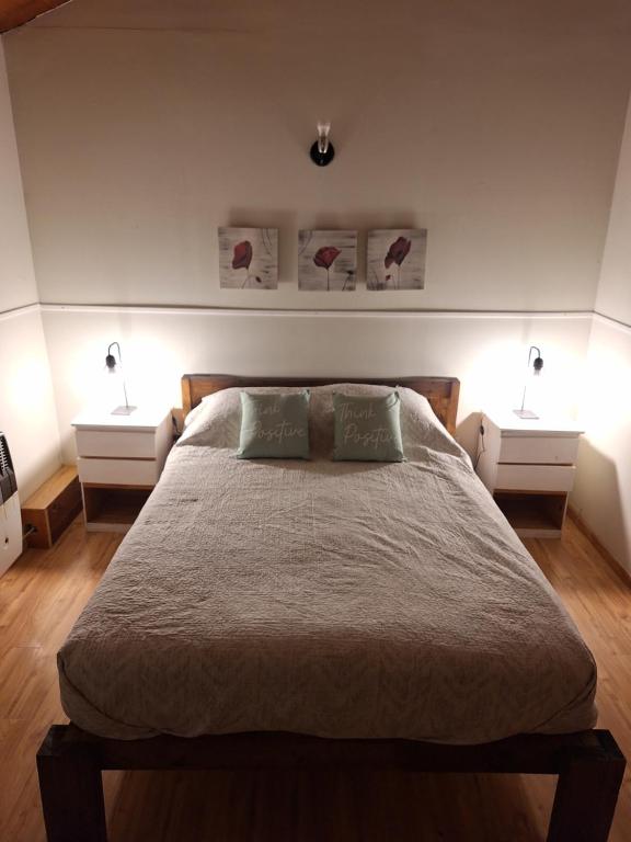 a bedroom with a large bed with two night stands at Departamentos Temporarios Cabañas Ushuaia in Ushuaia