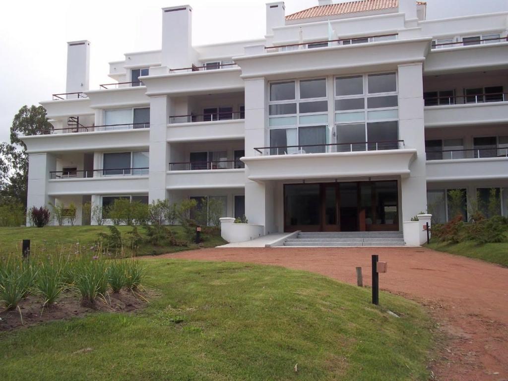 a large white building with a lawn in front of it at Green Park Punta del Este in Punta del Este