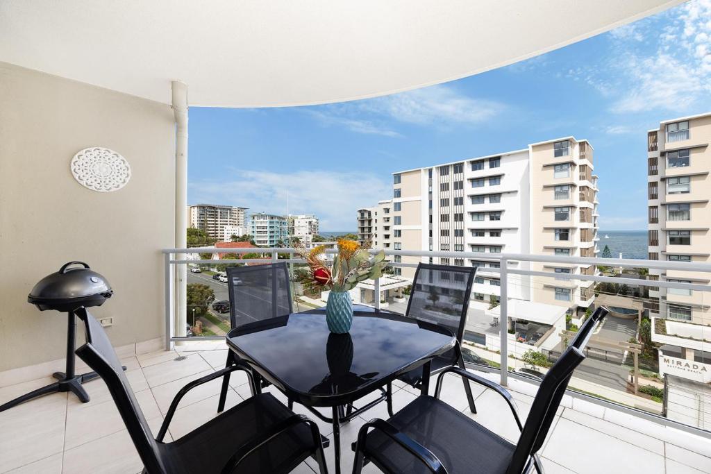 a table and chairs on a balcony with a view at Suttons Cove in Redcliffe