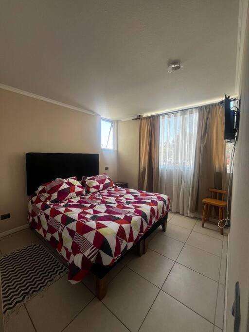 1 dormitorio con 1 cama con manta roja y blanca en Departamento en Huasco, Atacama en Huasco