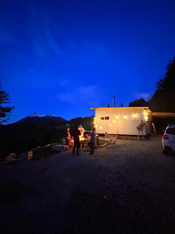 un grupo de personas de pie fuera de una casa por la noche en refugio lonconao, en Futaleufú
