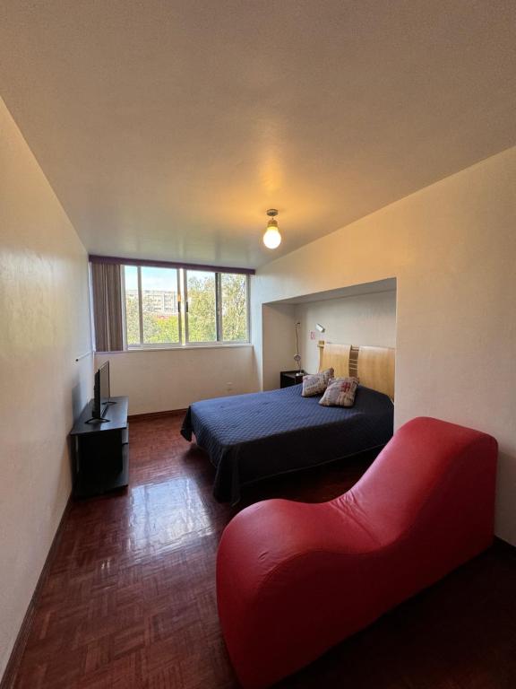 Un dormitorio con una cama y un sofá rojo. en Habitación amplia e indep c/ jacuzzi, céntrica., en Ciudad de México