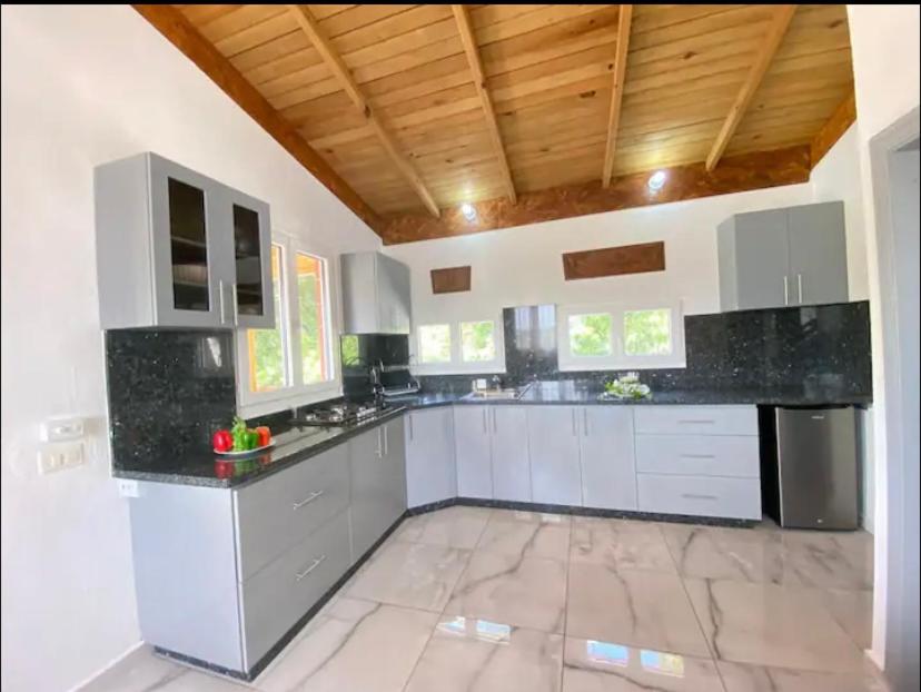 uma grande cozinha com balcões brancos e um tecto de madeira em Fantástico espacio para alojarse em Puerto Palenque