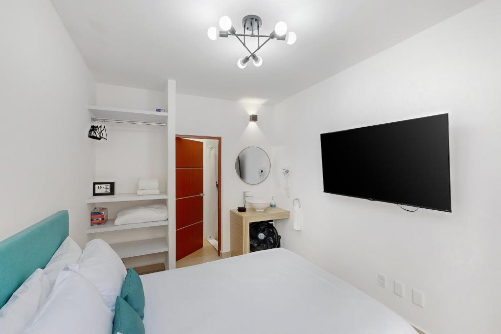 sypialnia z łóżkiem i telewizorem z płaskim ekranem w obiekcie Blooming Hideaway @ Cadetes 303 w mieście Meksyk
