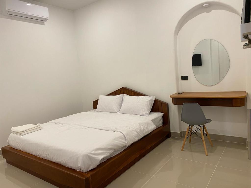 a bedroom with a bed with a mirror and a chair at B2 Hotel Savannakhet in Savannakhet